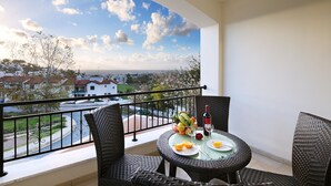 Ein Balkon mit Korbstühlen, einem runden Tisch und Blick auf eine Stadt.