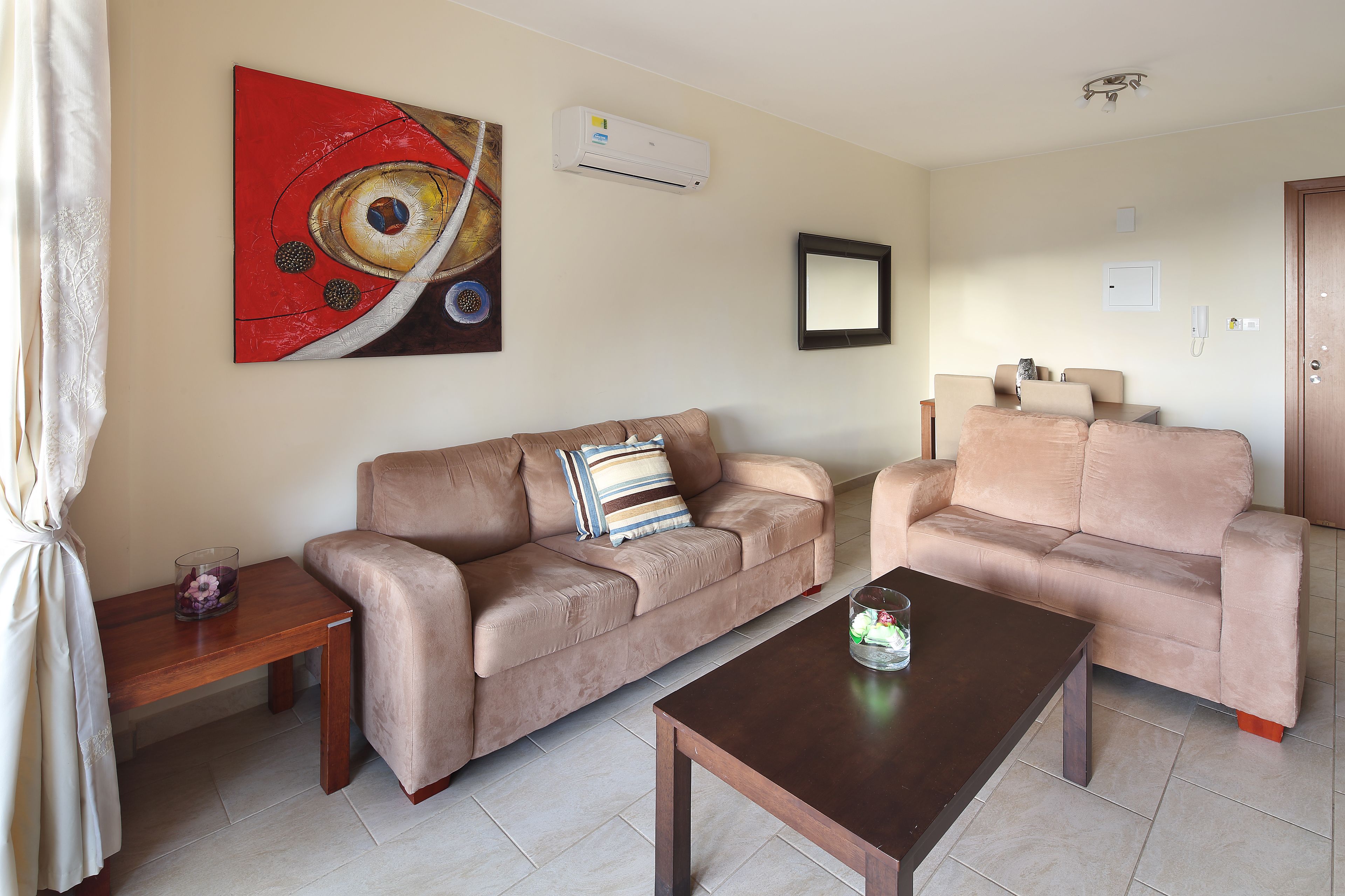 A living room with two sofas, a coffee table, a painting, and an air conditioning unit.