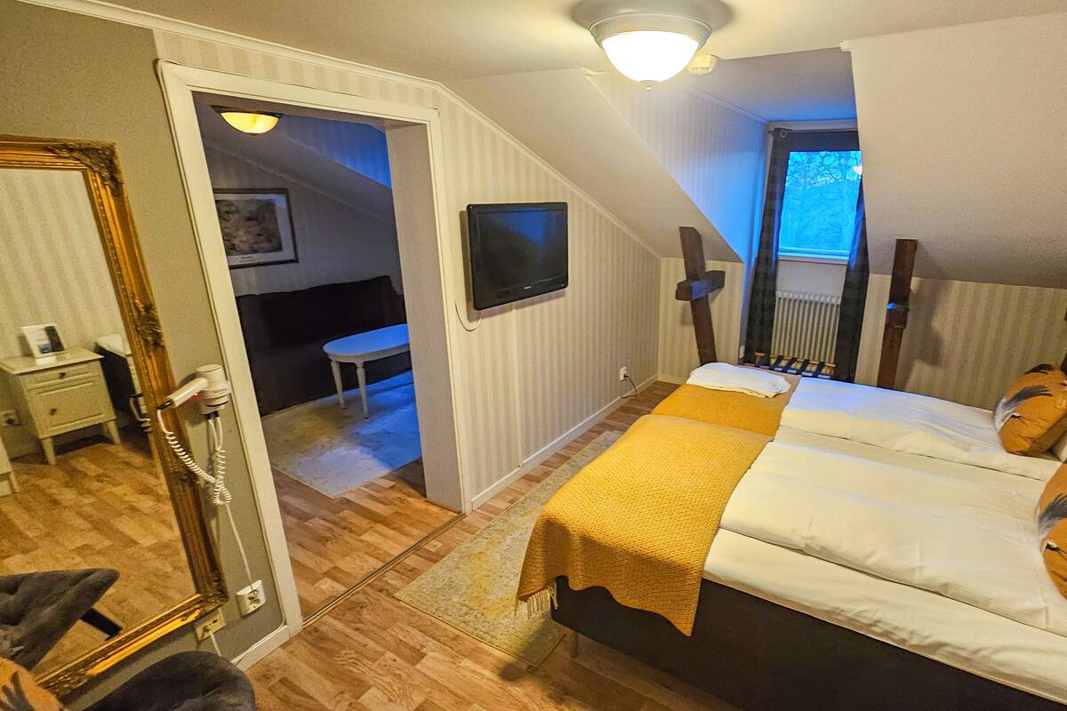 Un dormitorio con cama, escritorio, silla, televisor y ventana.