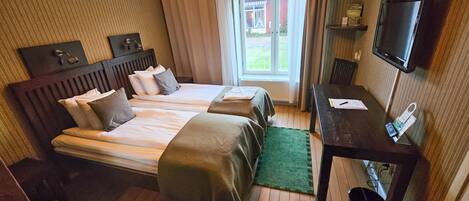 Une chambre d’hôtel avec deux lits, un bureau, une télévision et une vue sur l’extérieur.