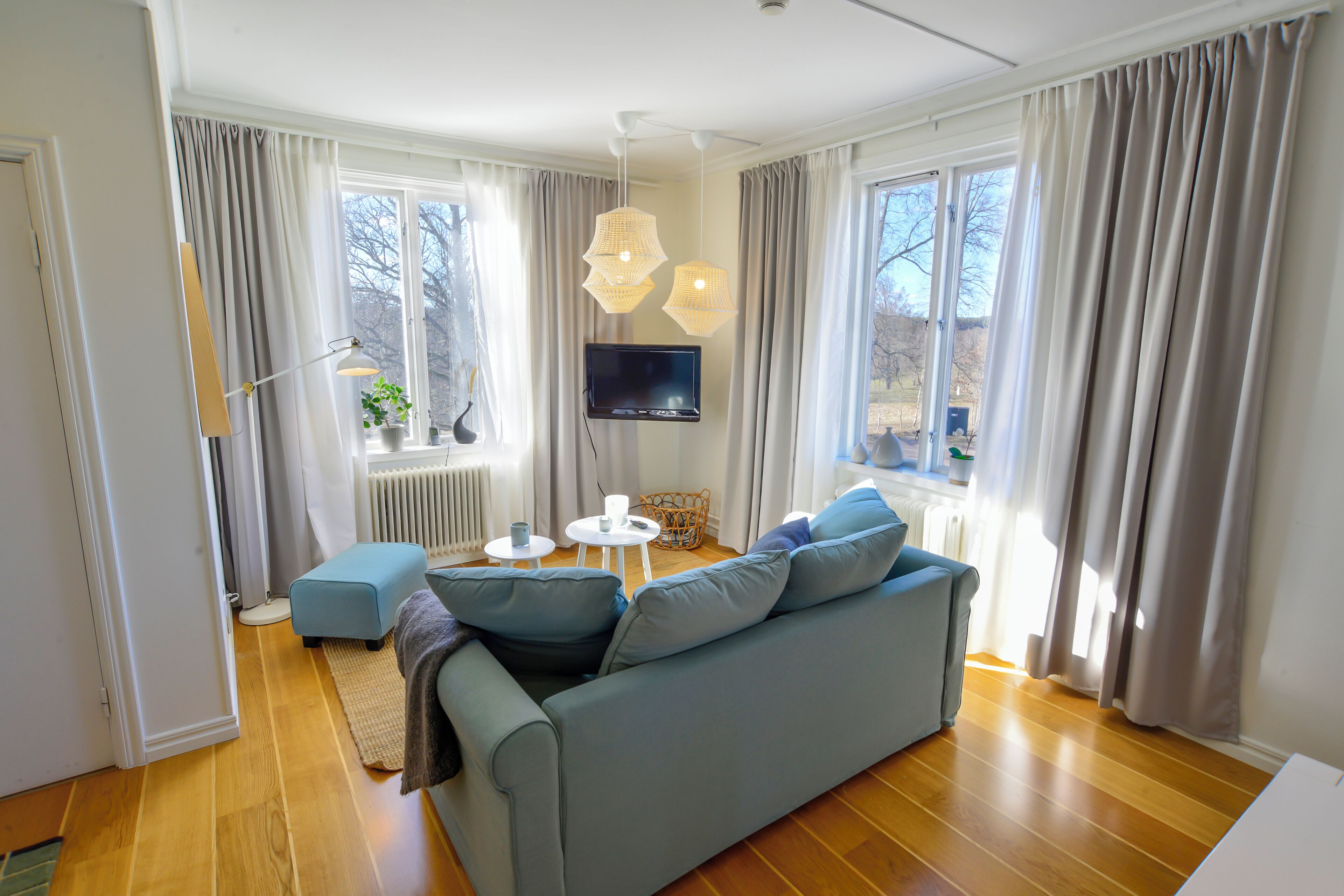 A living room with a sofa, a television, a small table, and a window with curtains.