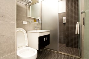A modern bathroom with a toilet, sink, and shower area. - RA Guesthouse (Hualien City)