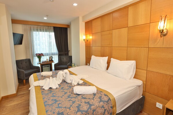 Habitación de hotel con una cama grande, un sofá, un televisor y una ventana con cortinas.