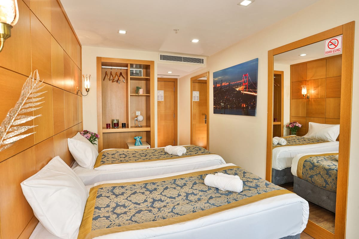 A hotel room with two beds, wooden headboards, a night view poster, and a no smoking sign.