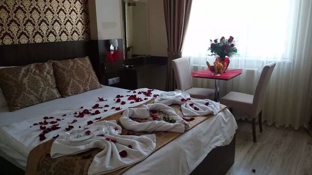 Una habitación de hotel con una cama bien hecha, una mesita con un florero y una silla.