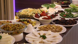 Una mesa de buffet con diversos platos, incluyendo ensaladas, carnes y quesos.