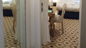 Een slaapkamer met een bed, een stoel, een spiegel en een uitschekkingsbord.