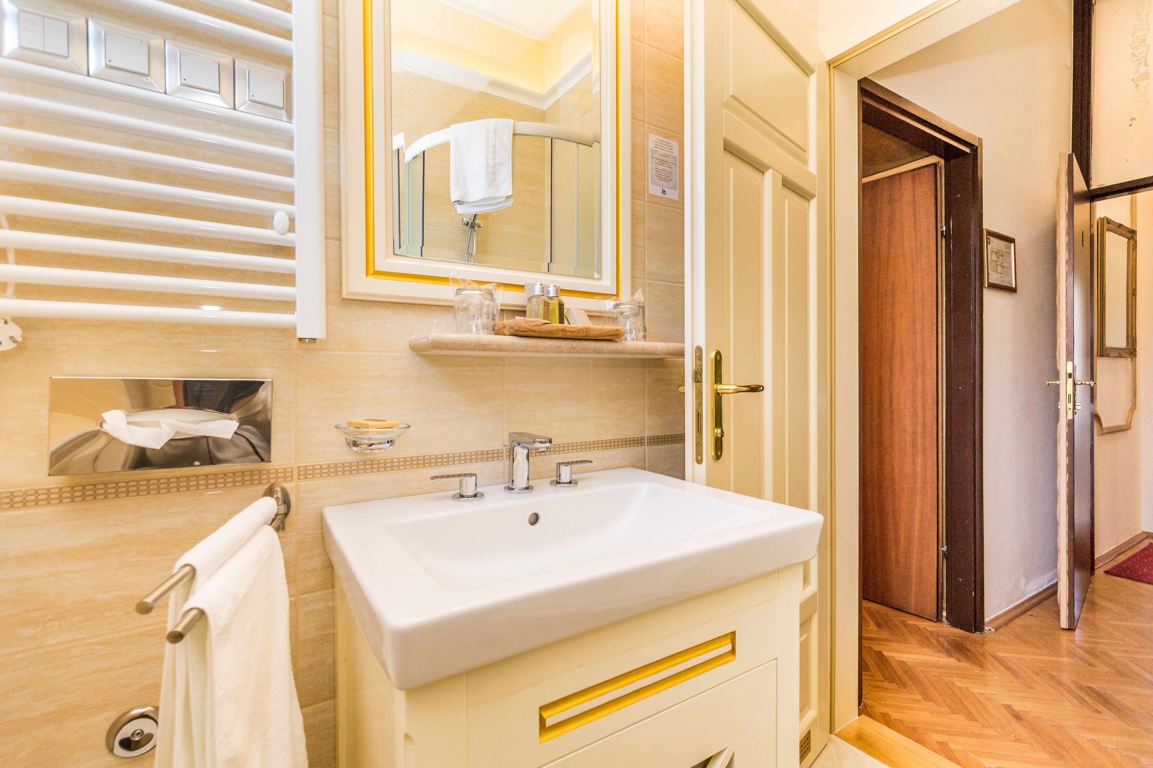 A modern bathroom with a large sink, mirror, and towel rack.