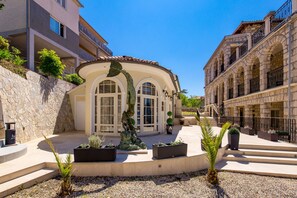 Un edificio con fachada curva, ventanas amplias y un muro de piedra.