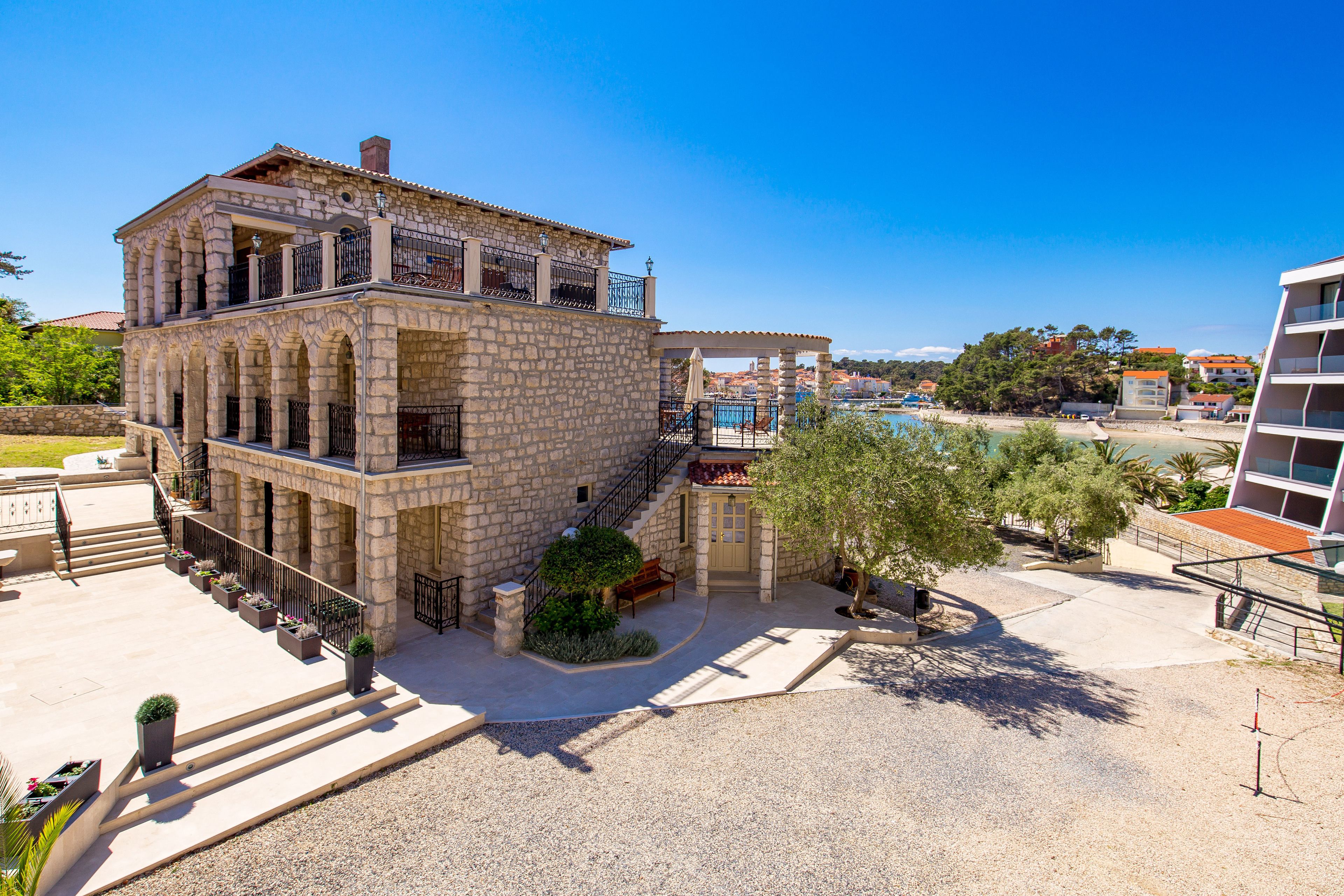 Ein Gebäude aus Stein mit Balkon, Treppe und Poolbereich.