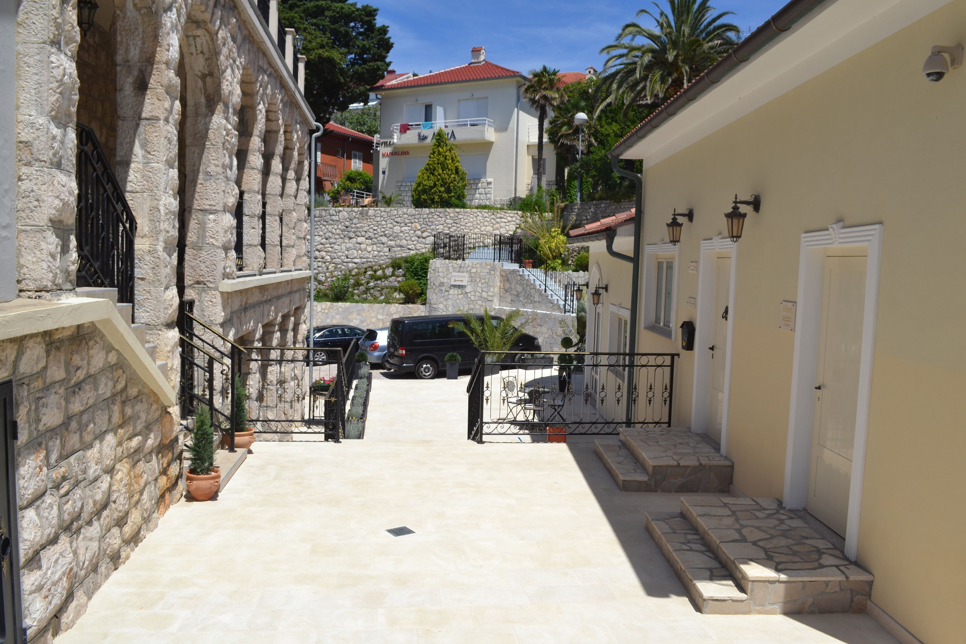 A narrow street leading to a building with a stone facade and a red roof.