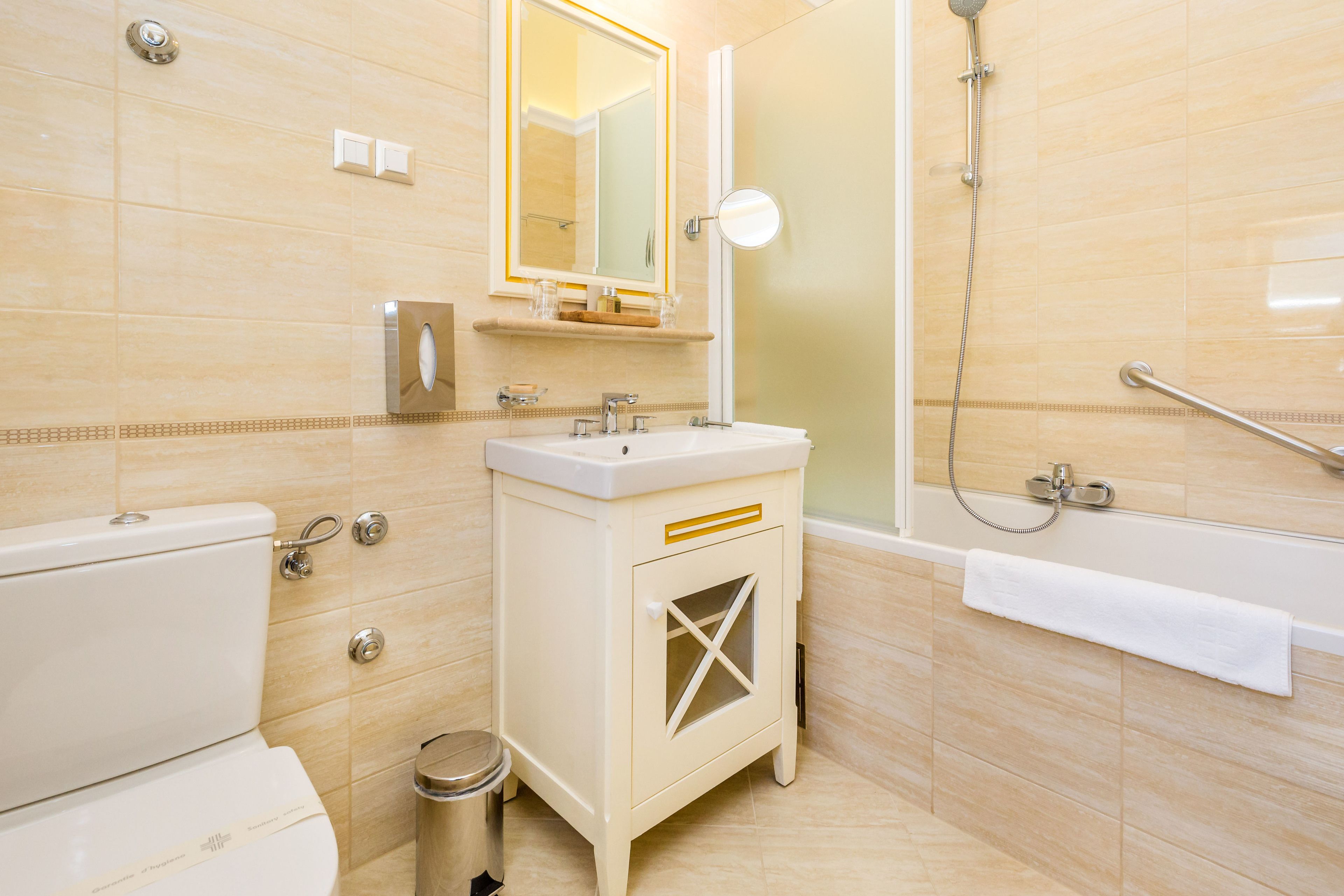 A bathroom with a toilet, sink, vanity, mirror, shower, and bathtub.