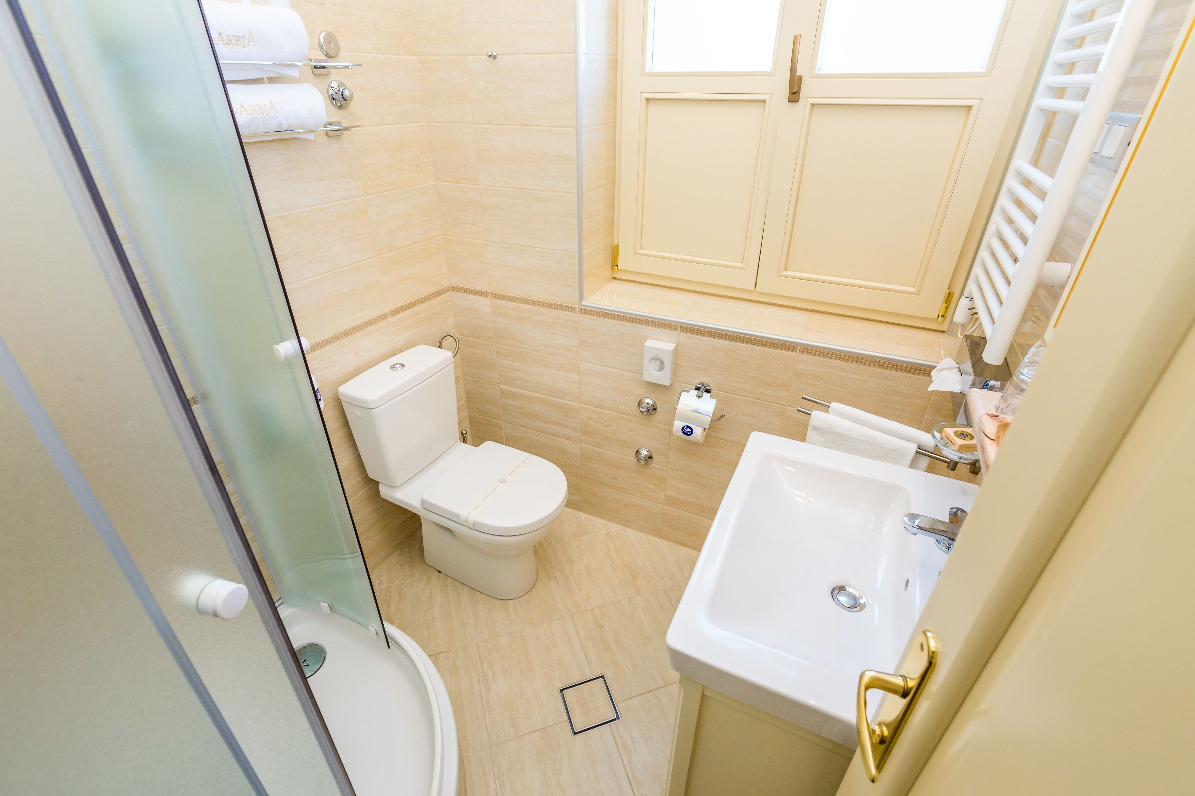 A bathroom with a toilet, sink, and glass shower enclosure.