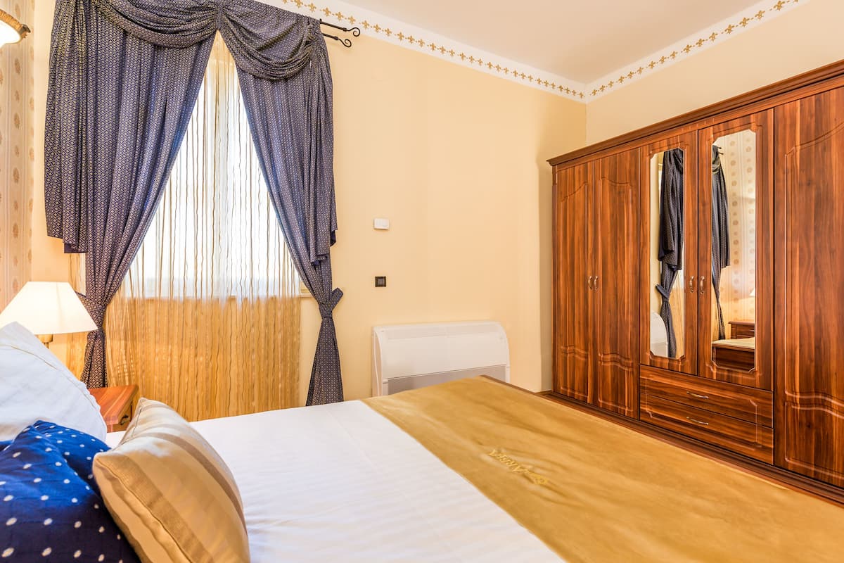 Una habitación de hotel con cama, armario y ventana con cortinas.