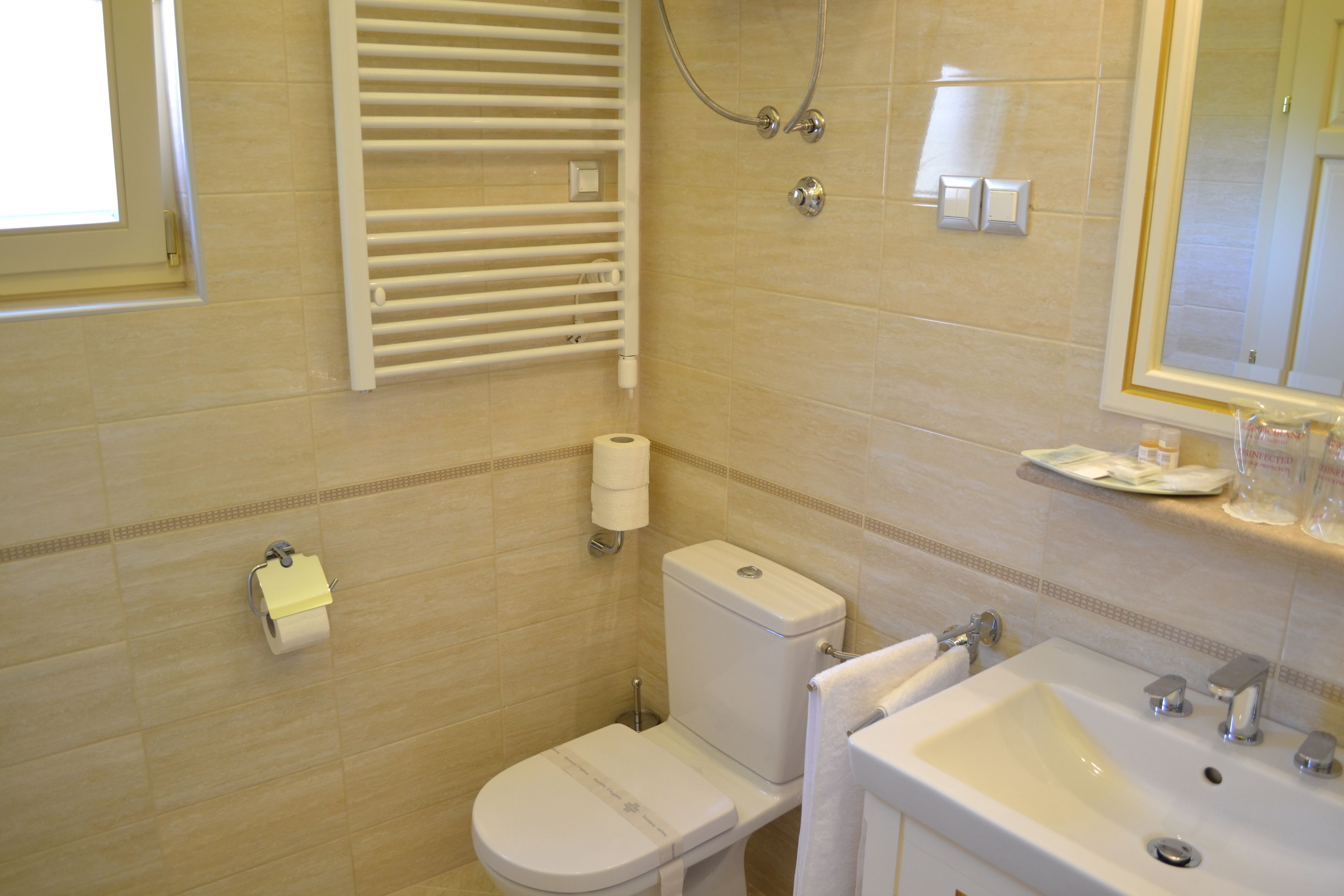 Un baño con inodoro, lavamanos, toallero y espejo.
