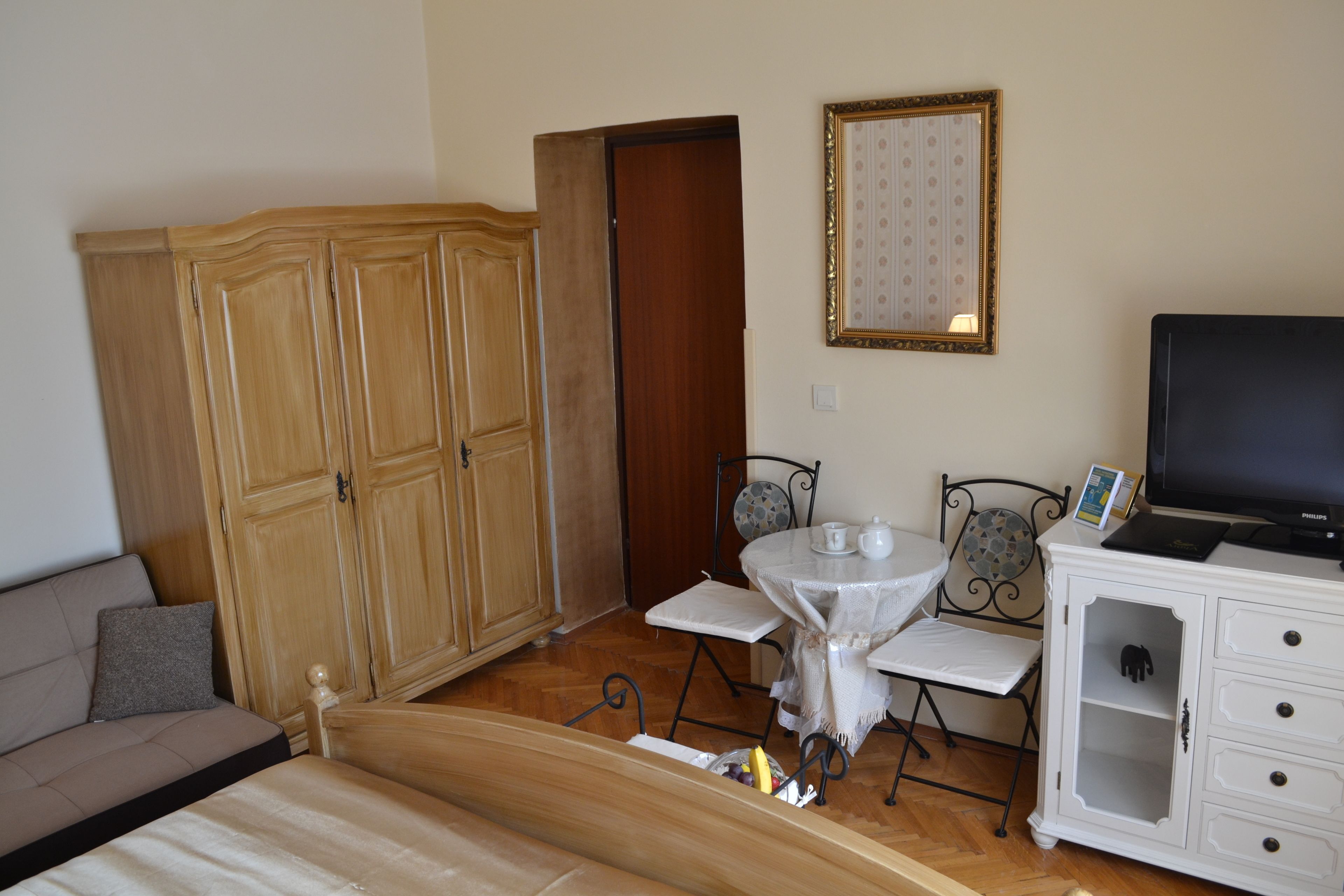 Ein Zimmer mit einem Bett, einem Kleiderschrank, einem Esstisch mit Stühlen, einem Fernseher und einem Schrank.