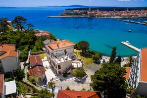 A coastal town with a prominent church, clear blue sea, and traditional buildings. - Integrated Hotel Arbia-Margita (Rab)
