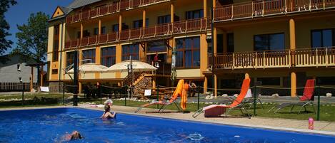 Una piscina al aire libre, sillones reclinables de piscina