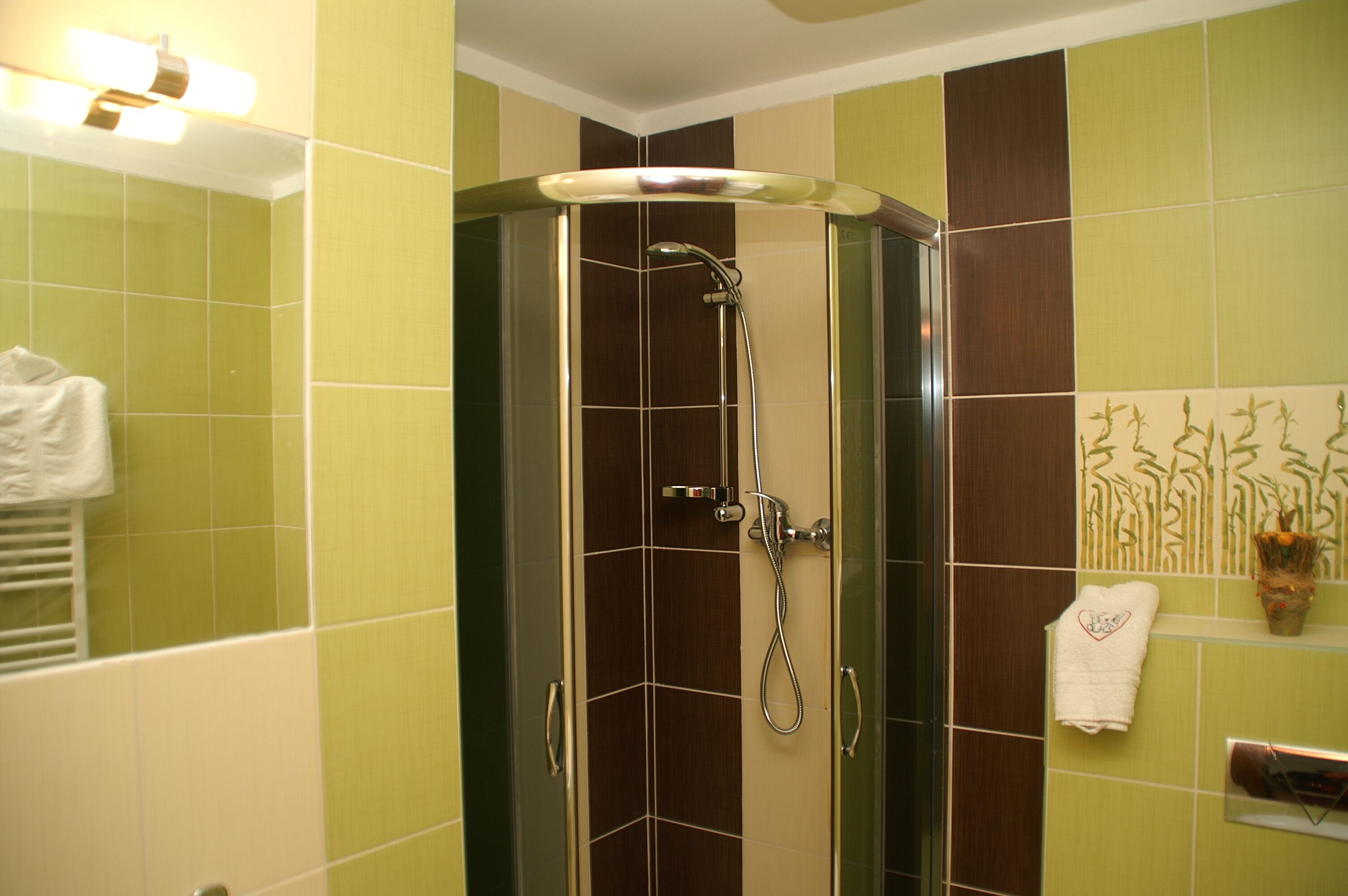 A shower with a glass door, a towel rack with a towel, and a wall with a decorative tile pattern.