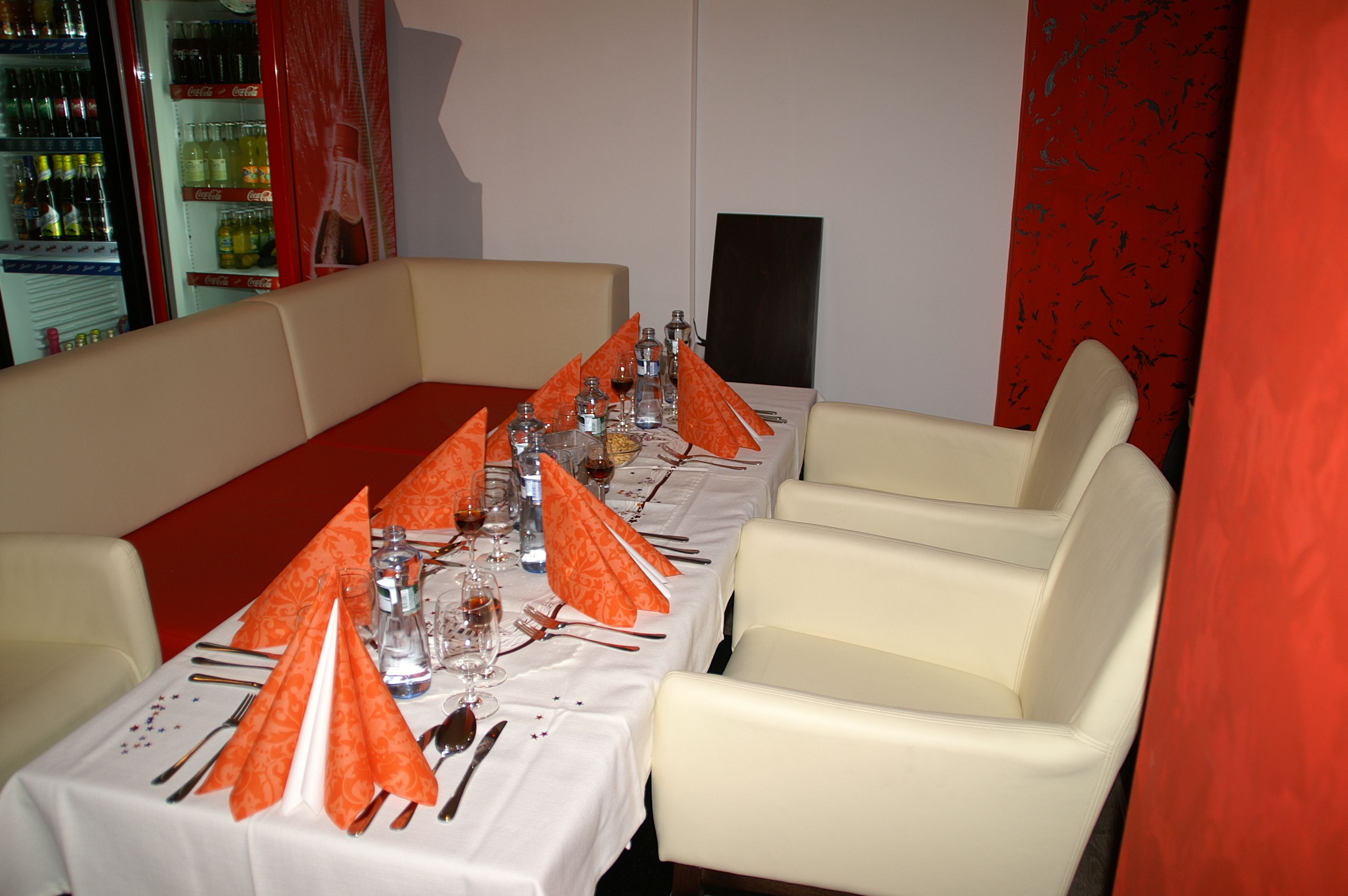 Un comedor con una mesa larga dispuesta para una comida, rodeada de sillas blancas acolchadas.