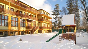 A multi-story hotel with balconies, a snow-covered playground, and a ski lift. - Hotel Avalanche (Stola)