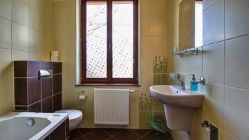 A bathroom with a bathtub, toilet, sink, and window.
