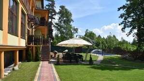 A building with a brick pathway leading to a covered outdoor seating area with tables and chairs. - Hotel Avalanche (Stola)