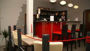 A restaurant with a bar area, red and black chairs, and a potted plant.