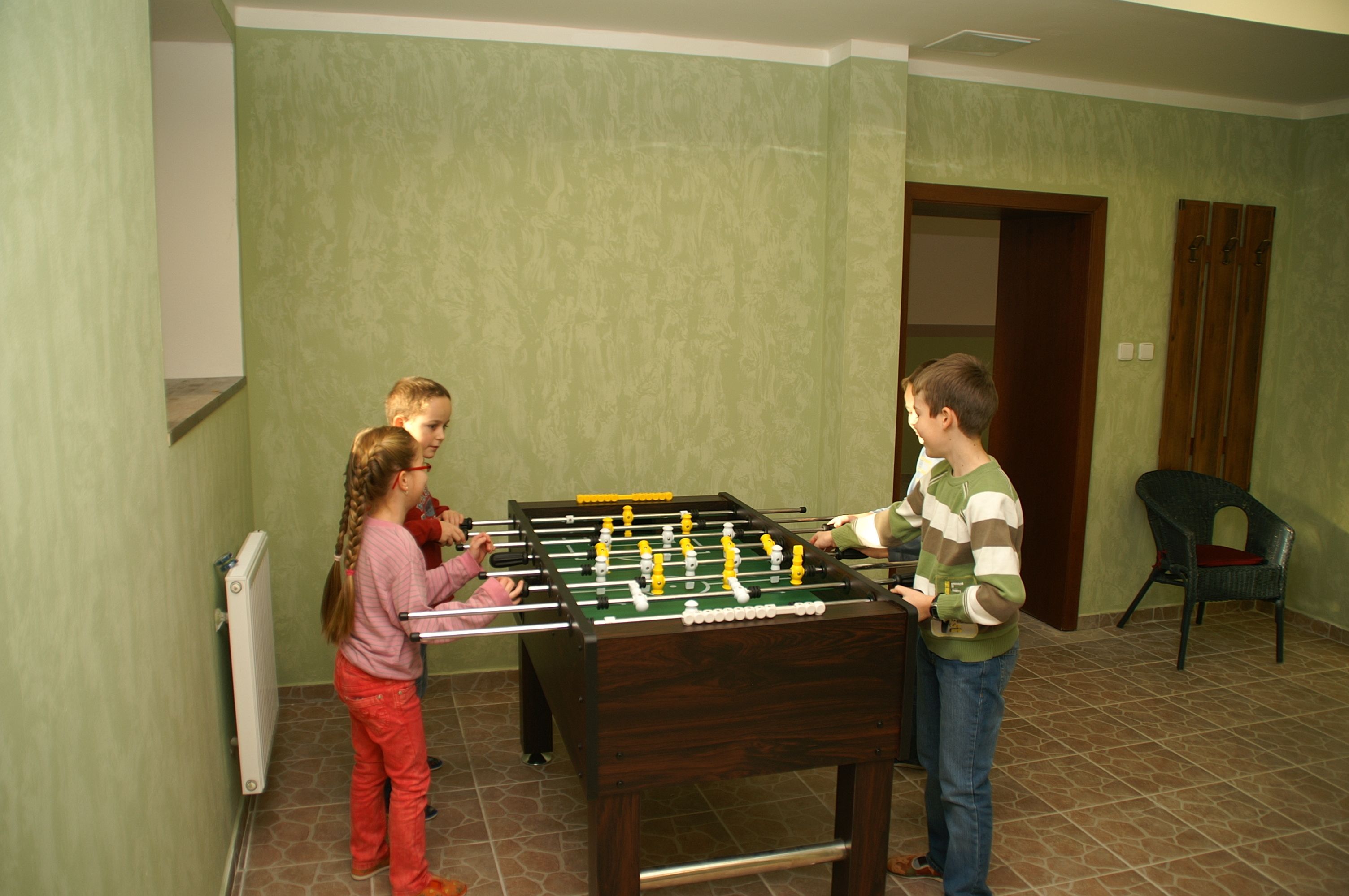 A room with a foosball table, a radiator, and a door leading to another room.