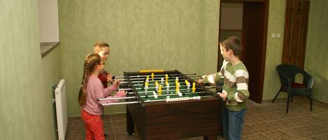 A room with a foosball table, a radiator, and a door leading to another room.