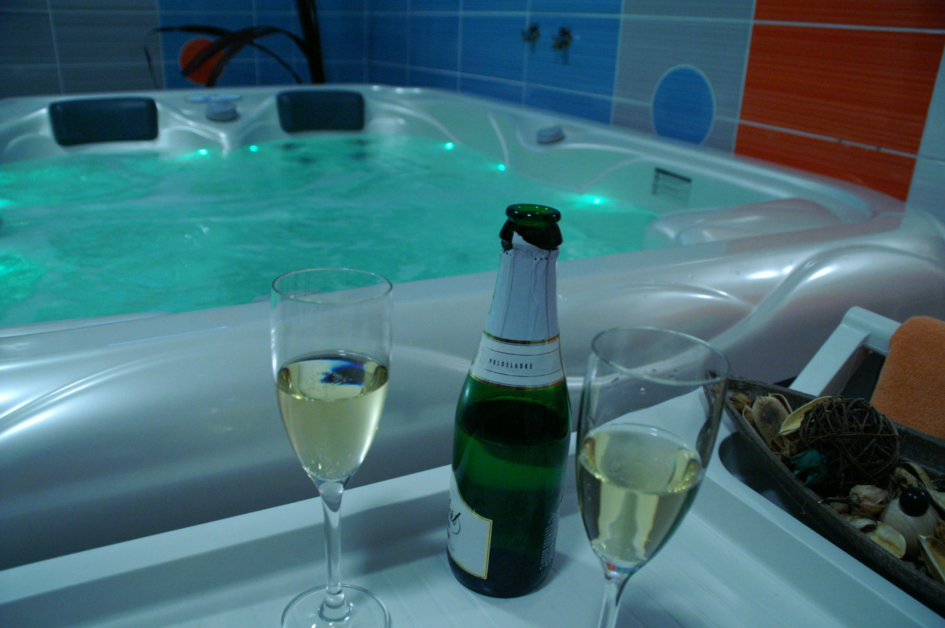 Un jacuzzi con una botella de champán y copas de vino blanco.