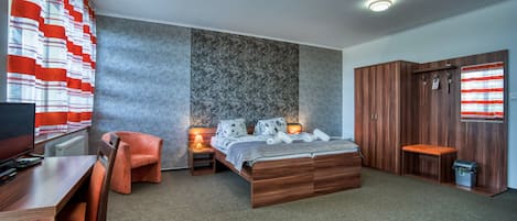 A modern bedroom with a large bed, a desk, a chair, and a wardrobe.