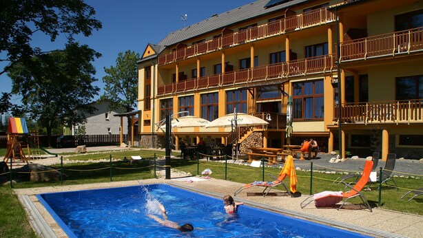 A swimming pool with a person swimming, surrounded by lounge chairs and umbrellas. - Hotel Avalanche (Stola)