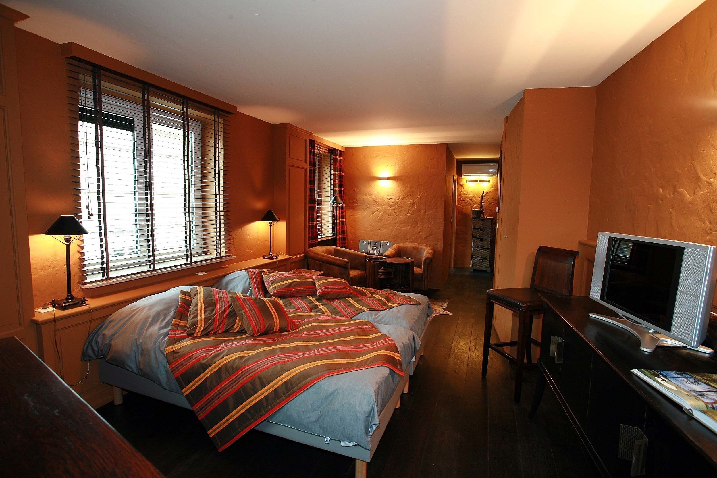 Quarto com duas camas, uma escrivaninha com televisão e uma cadeira.