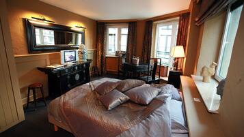 Habitación de hotel con una cama grande, un escritorio, una silla, un aparador y una ventana con cortinas.