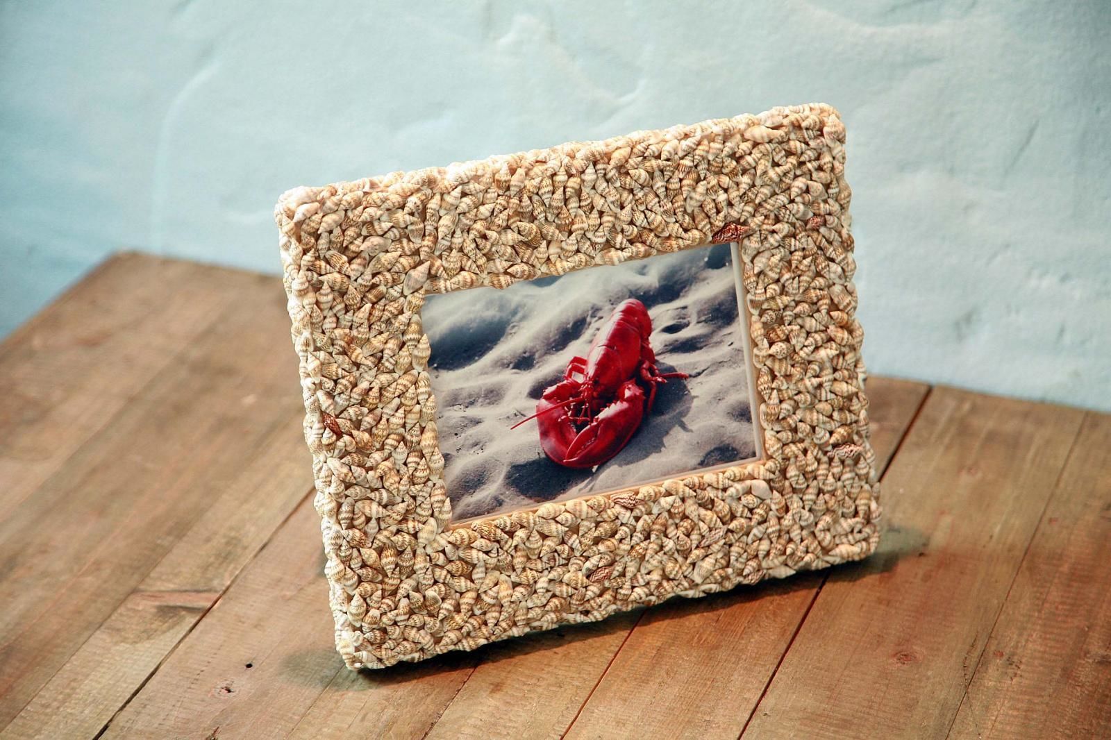 A framed picture with a seashell border on a wooden surface.