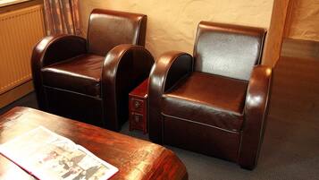 A room with two leather armchairs, a small wooden side table, and a magazine on the table.