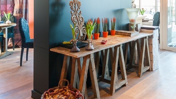 A modern kitchen with a dark accent wall, a wooden table, and potted plants. - De Laurier (Knokke-Heist)