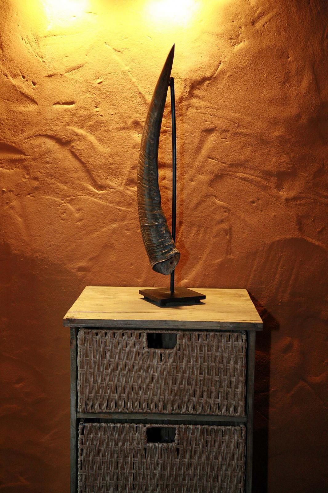 Una escultura sobre una mesa de madera frente a una pared con textura.