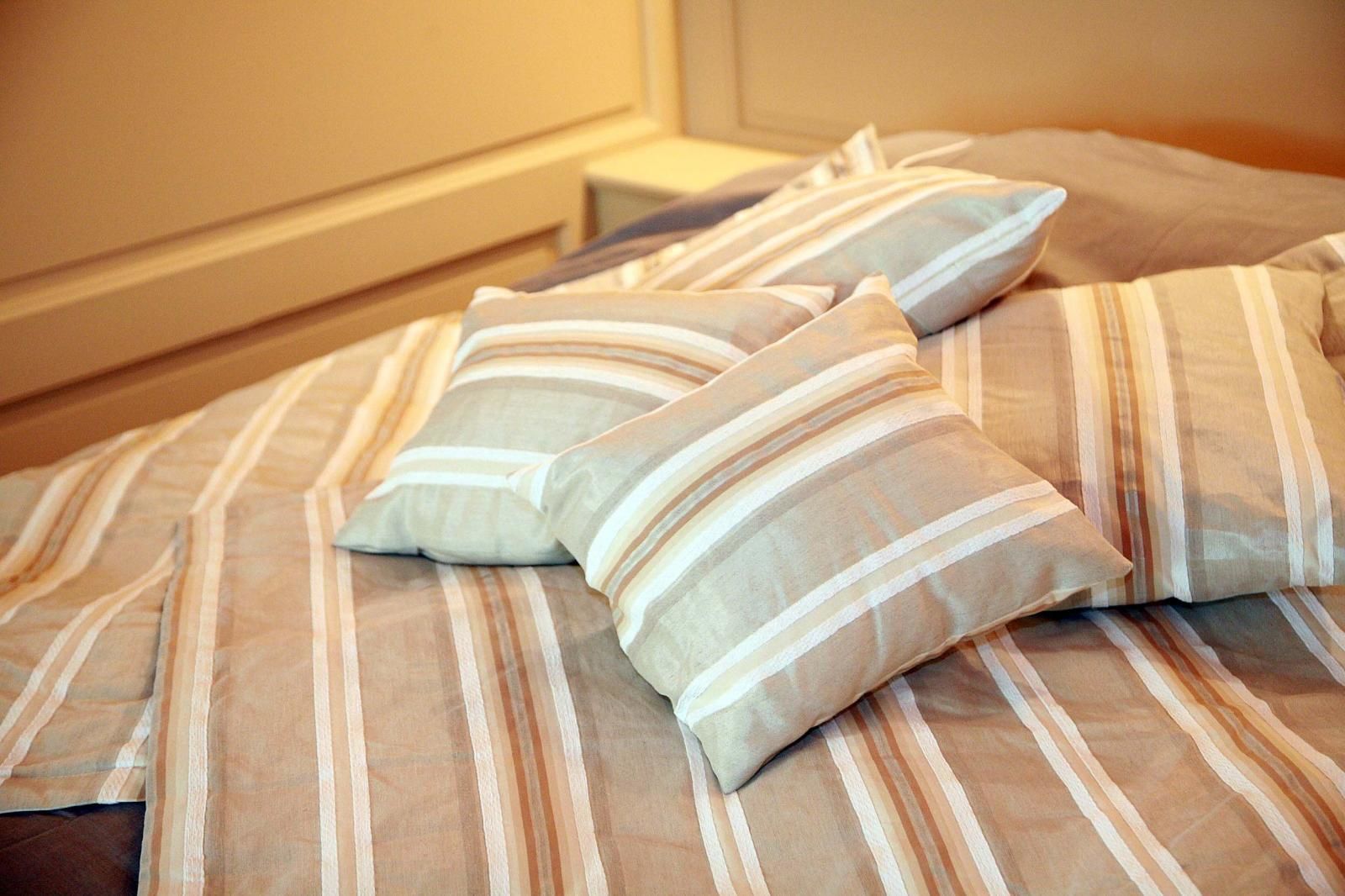 A bed with striped bedding and pillows.