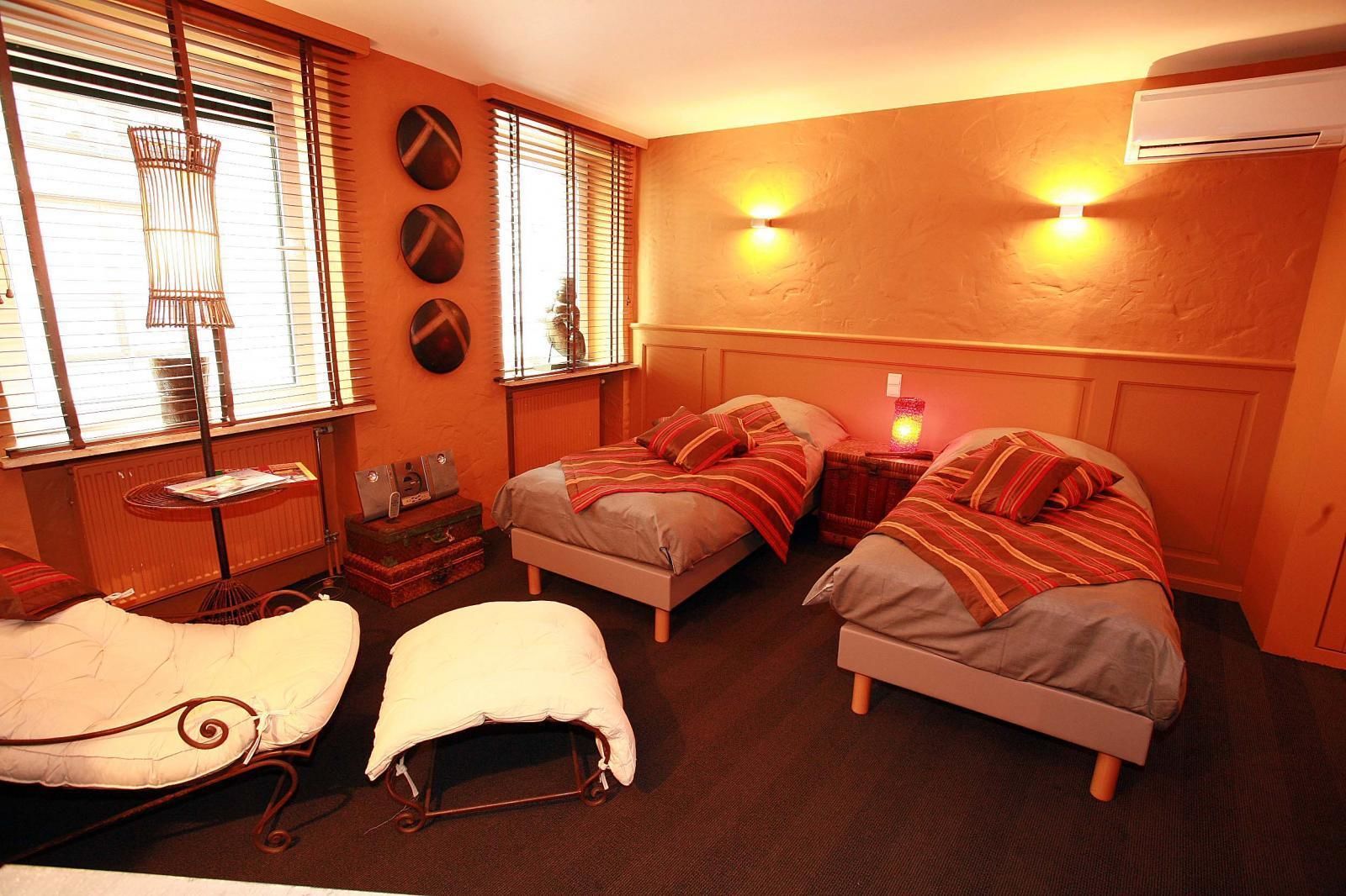 A cozy bedroom with two beds, a small table, and a radiator.