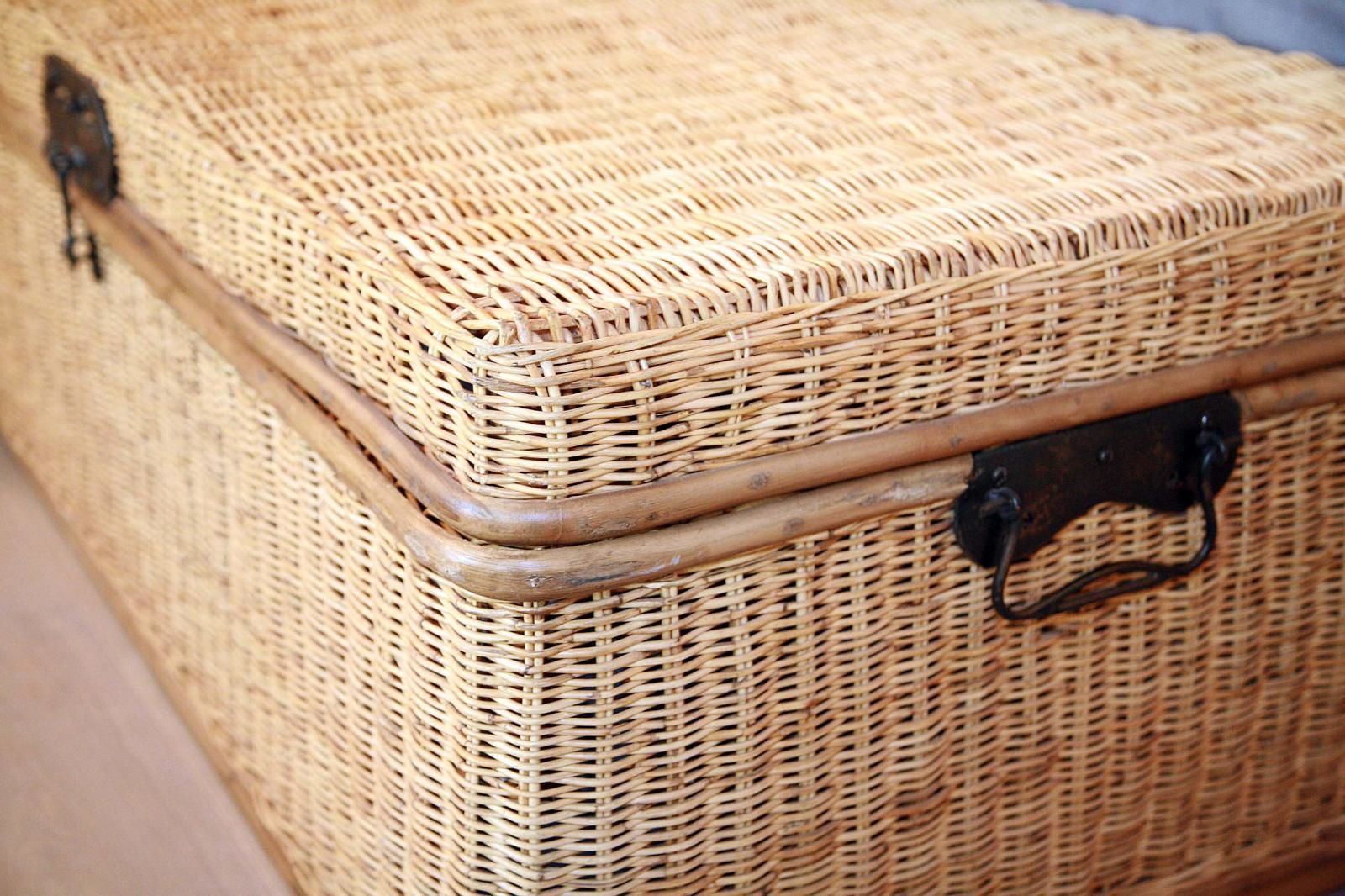 Une valise en osier, dotée d’une fermeture métallique et d’une poignée.