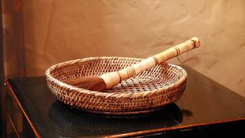 A woven basket with a wooden handle on a reflective black surface.