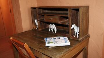Een houten bureau met een tijdschrift, een kleine witte paardjesbeeldje en een lade.
