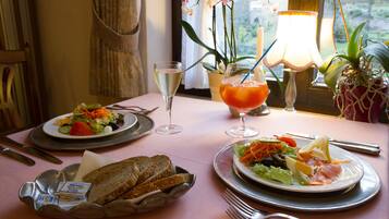 A dining table with plates of food, a basket of bread, and a glass of wine.
