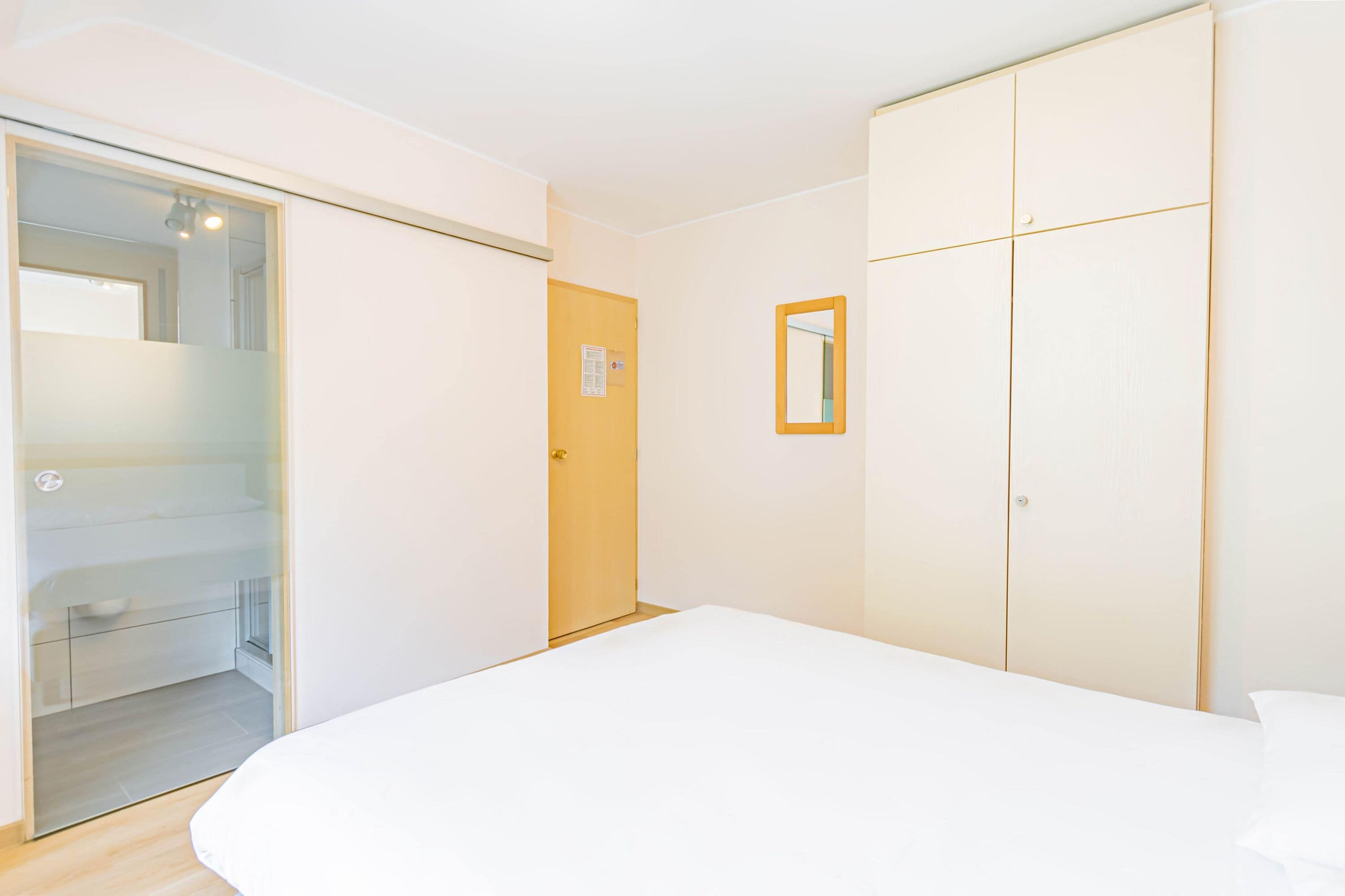A bedroom with a bed, a wardrobe, and a door leading to a bathroom.