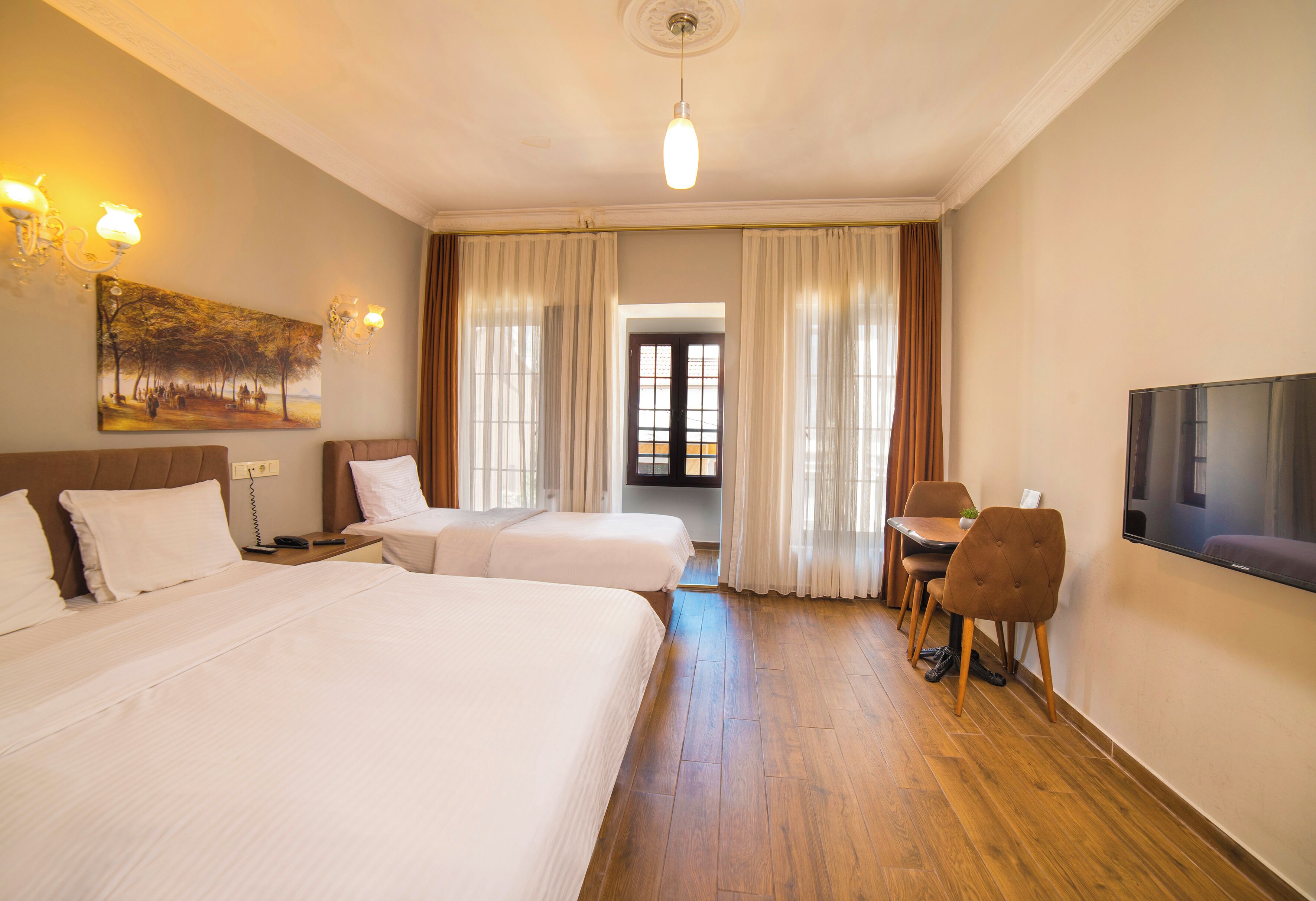 Una habitación de hotel con dos camas, televisión, mesa de comedor con sillas y un cuadro en la pared.