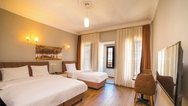 A hotel room with two beds, a desk, a chair, a television, and a painting on the wall. - Zendy Suite Hotel (Istanbul)