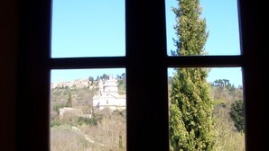 A window with four panes, each displaying different views: a clear blue sky, a tree, a building with domes, and a landscape with trees and a stone wall. - Relais San Bruno (Montepulciano)