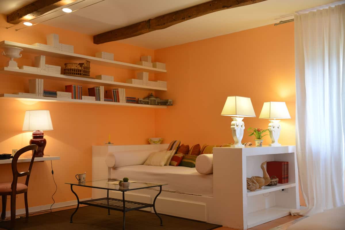Ein Wohnzimmer mit einem weißen Sofa, einem Glastisch und Regalen mit Büchern und Dekoration.